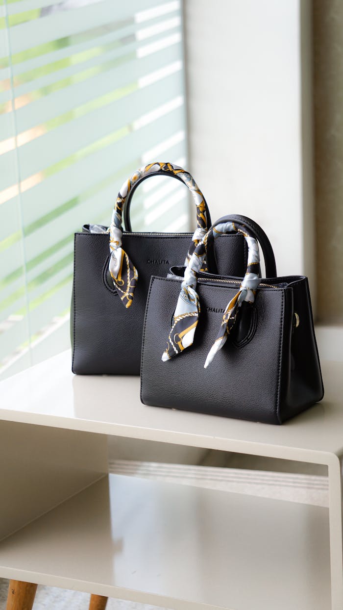 Stylish black leather handbag with decorative handles on a minimalist shelf.